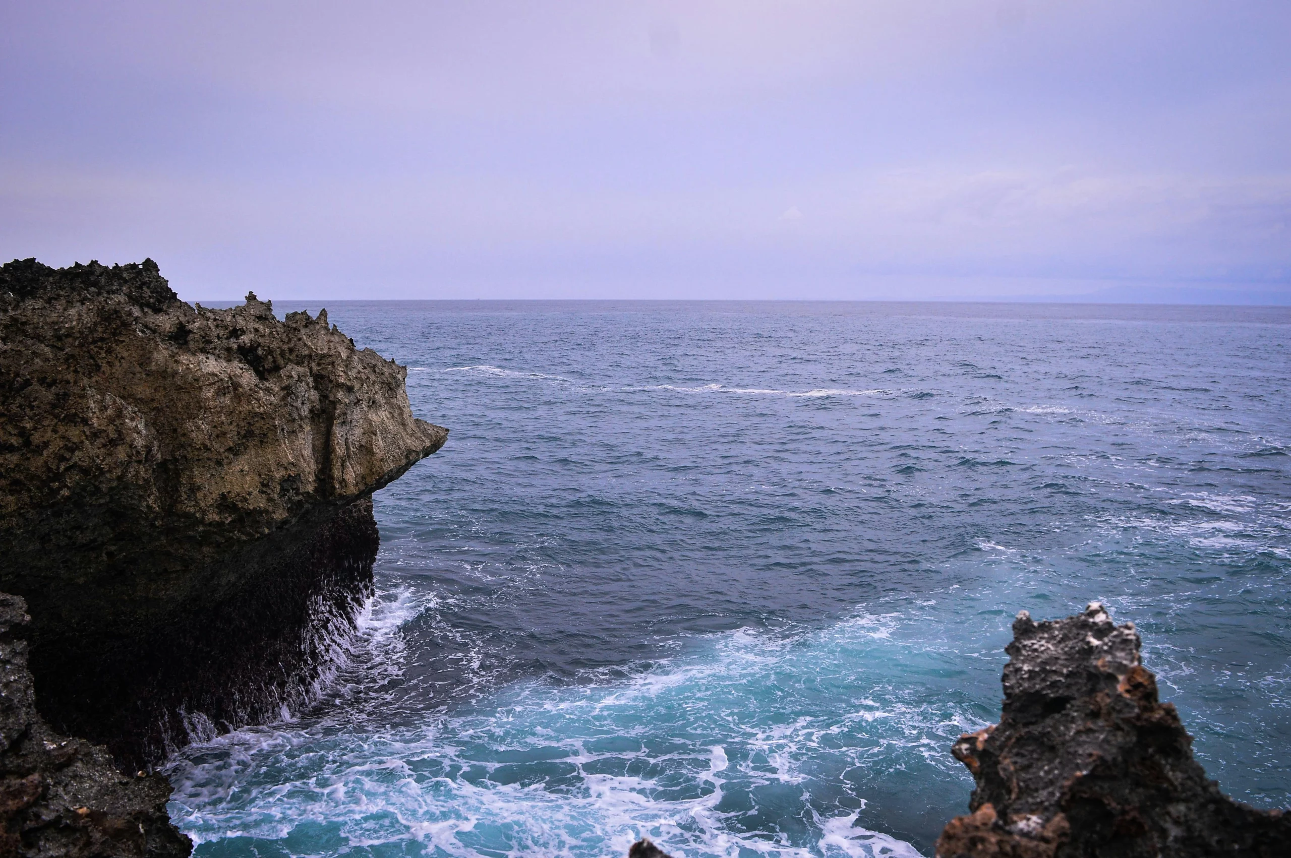 Voyage entre femmes en Indonésie : côte rocheuse et mer agitée sous un ciel pastel – Salma Travel