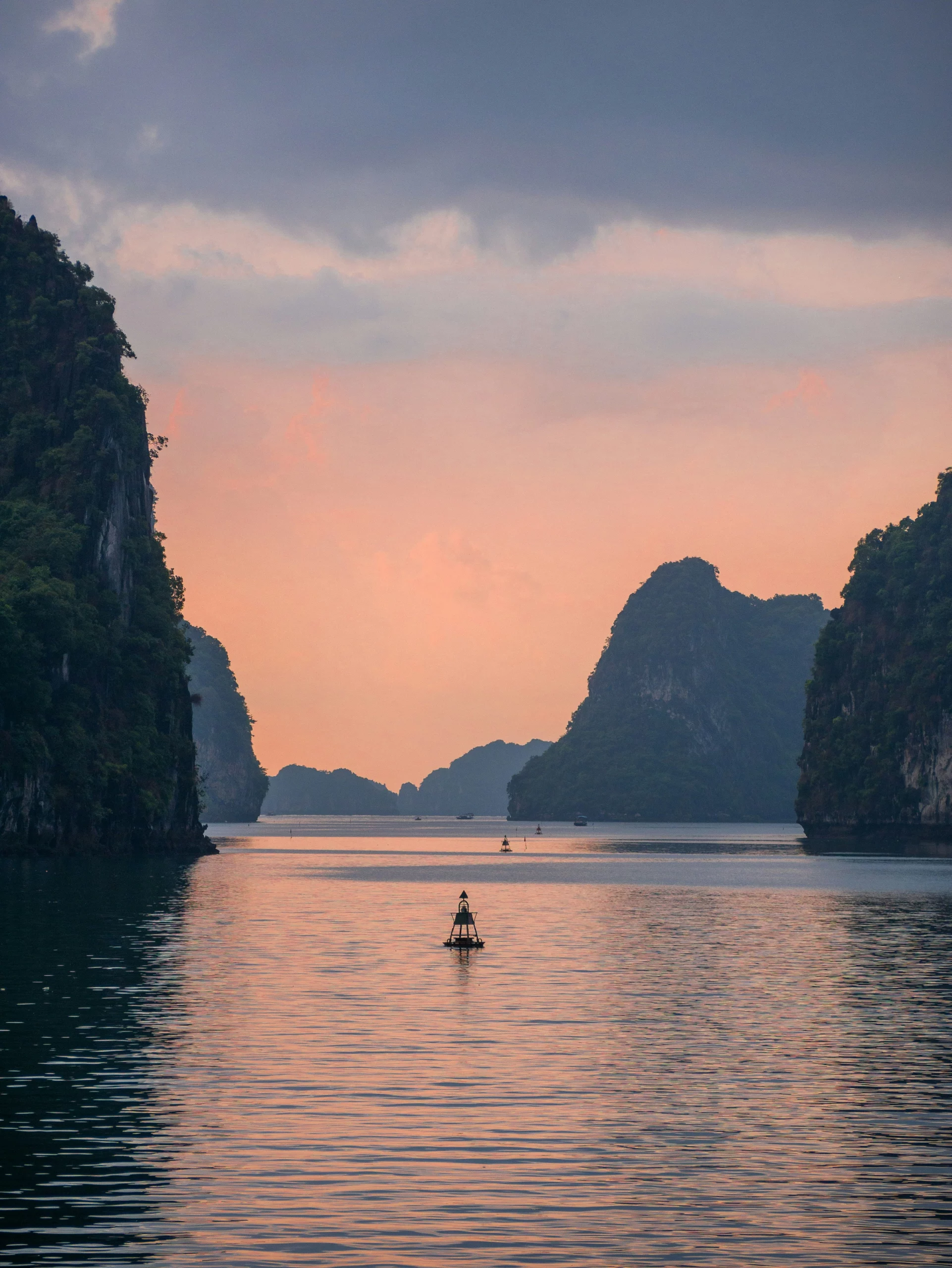 Voyage entre femmes au Vietnam : paysage de la baie d’Ha Long avec pitons karstiques et barque au coucher du soleil – Salma Travel