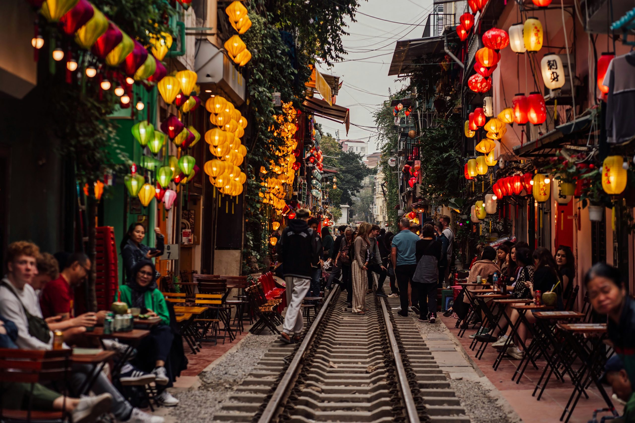 Voyage entre femmes au Vietnam : rue des rails à Hanoï animée avec cafés et lanternes colorées – Salma Travel