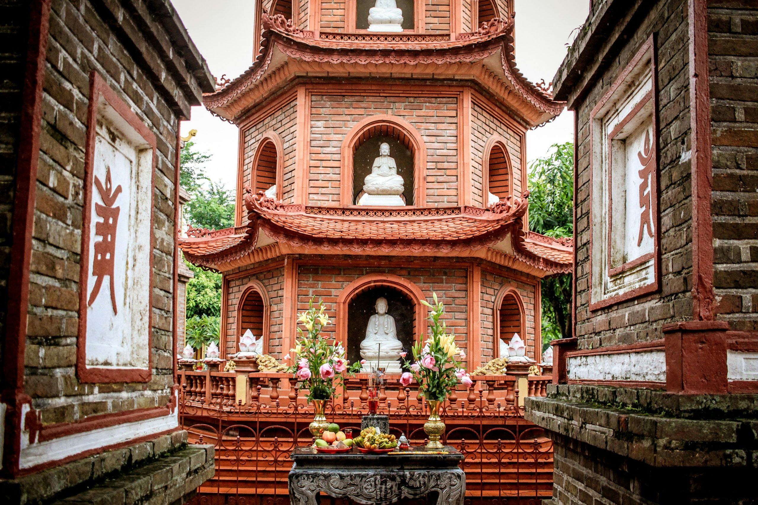 Voyage entre femmes au Vietnam : pagode Tran Quoc en briques rouges à Hanoï avec statues de Bouddha et offrandes – Salma Travel