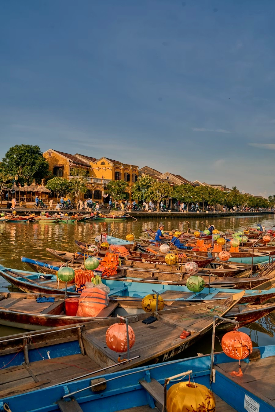 Voyage entre femmes au Vietnam : barques colorées et lanternes sur la rivière à Hoi An avec maisons jaunes du centre historique – Salma Travel